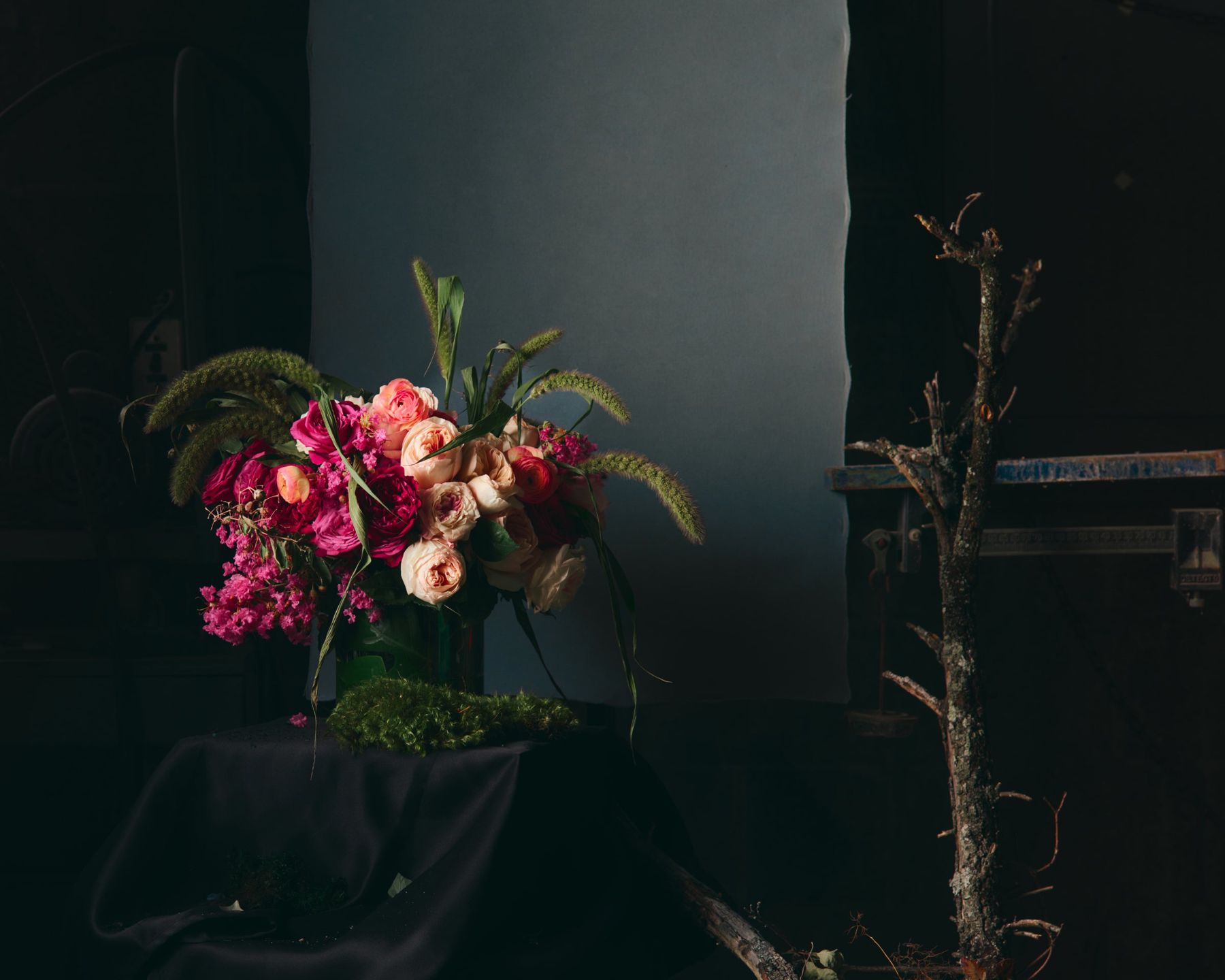 Magenta roses and orchids arranged against a dark studio backdrop