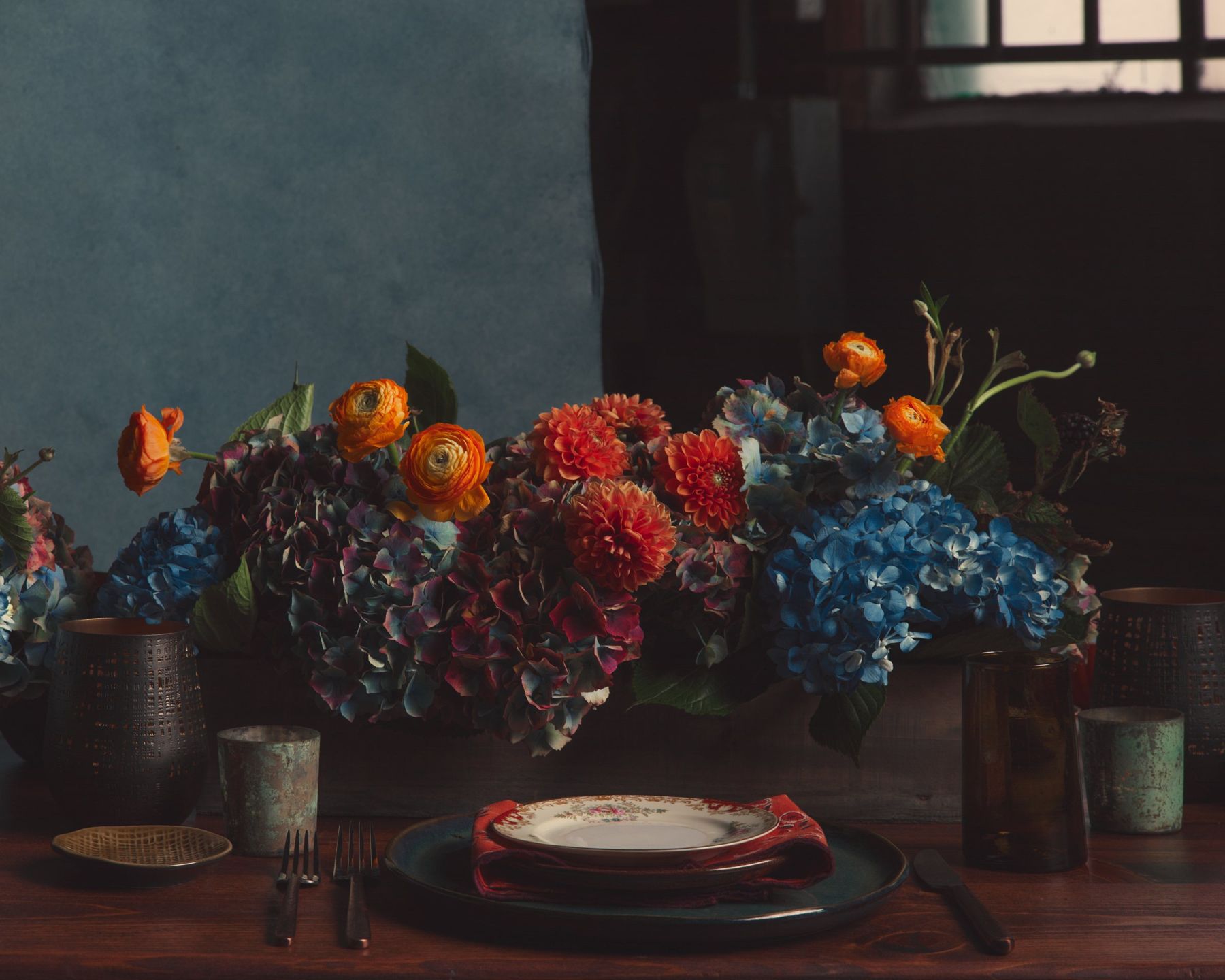 Dahlias and hydrangeas above a vintage place setting